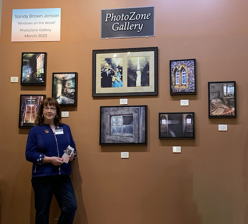 picture of photographer in front of a wall of her photos on a gallery wall